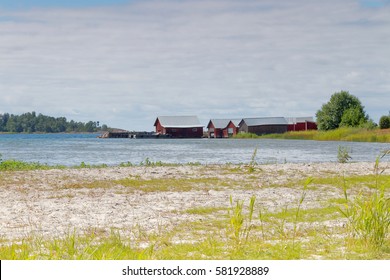 Distant red boathouses and a sand beach in the foreground in the archipelago in Aland, Finland