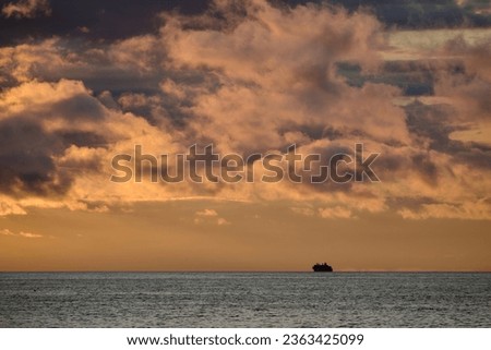 Distant ship sailing in peaceful sunset sea