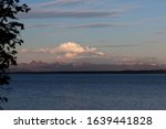 Distant storm clouds and mountains reflect the setting sun over Yellowstone Lake in Yellowstone National Park, Wyoming.