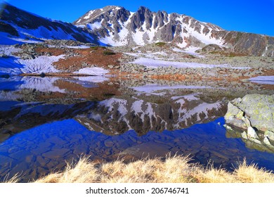 Distant summit reflected by mountain lake at sunrise