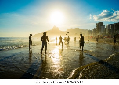 Distant Sunset Silhouettes Playing Keepy-uppie Beach Football On The Sea Shore In Ipanema Beach Rio De Janeiro Brazil