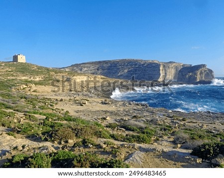 Distant tower of Dwejra overlooking beautiful landscape with a rocky seashore on the Island of Gozo (Malta)