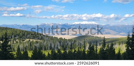 Distant view of the Madison Range from the Gravelly Range overlooking the Madison Valley beneath a bright Montana sky.