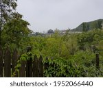 A distant view on the temple complex in Beijing, China. There is a five storied pagoda towering above the horizon. Thick bamboo forest overgrowing the area. A wooden fence in the front. Air pollution