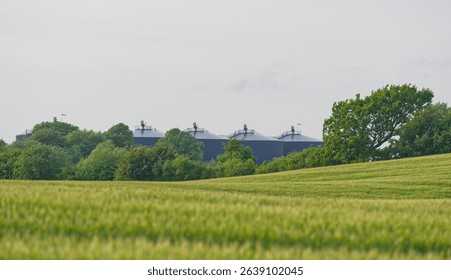 Distant view over fields to the BIO-Gas storage of the biogas site in Kvaers in Denmark also large black barrel-shaped storage