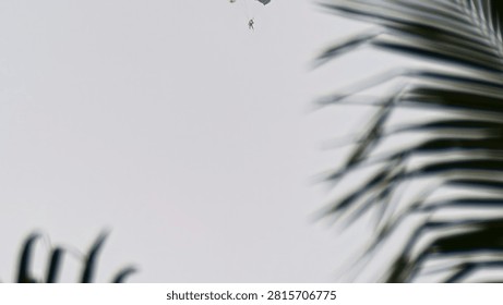 Distant view of a skydiver parachuting through a clear open sky during a skydiving descent