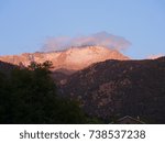 Distant view of the summit of Pikes Peak with tree tops early in the morning seen from Manitou Springs, Colorado