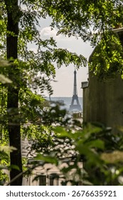 A distant view through the trees of the Eiffel Tower from Montmartre in Paris, France.
