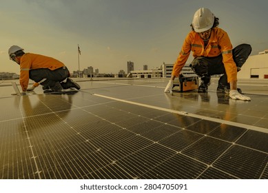 Distant workers against the setting sun move across the reflective rooftop at dusk overlooking the city, highlighting clean energy, occupational safety and the daily work of engineers.