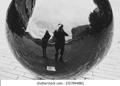 A distorted reflection of two people being created by a spherical ball. Parallel universe concept image.  - Shutterstock ID 1557894881
