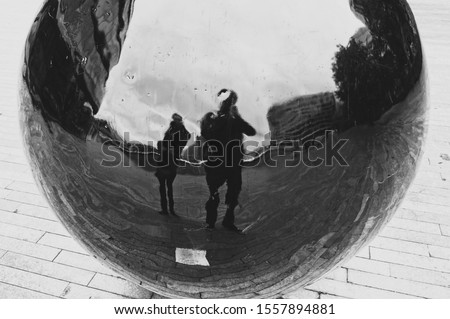 A distorted reflection of two people being created by a spherical ball. Parallel universe concept image. 