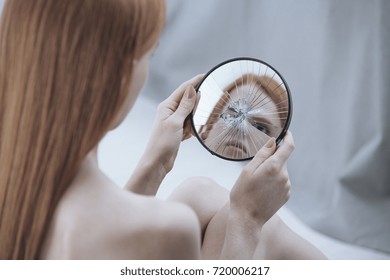 Distorted Reflection Of A Woman In A Small, Broken Mirror