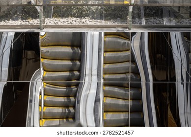 Distorted steps of escalator reflected in glossy architectural panels
