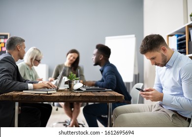 Distracted Businessman Using Mobile Phone In Meeting