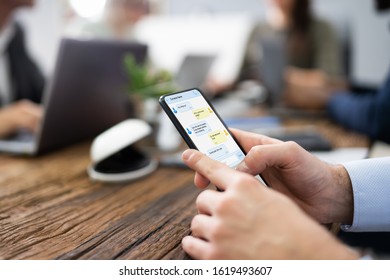 Distracted Businessman Using Mobile Phone In Meeting