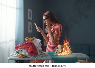 Distracted sorglose Hausfrau chattet mit ihrem Telefon, sie brennt Kleidung mit dem Eisen