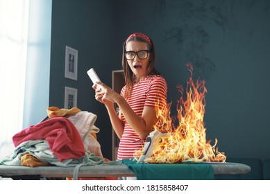 Distracted careless housewife chatting with her phone, she is burning clothes with the iron