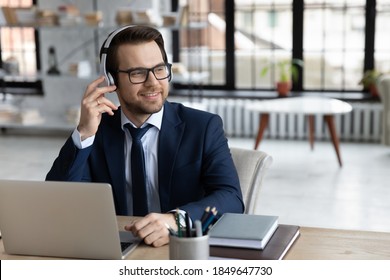 Distracted From Computer Work Happy Young Successful Businessman Wearing Modern Headphones, Enjoying Pleasant Music At Workplace, Relaxing In Office, Copy Space For Advertising No Stress Workday.