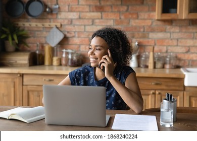 Distracted from computer work pleasant attractive young african american woman involved in cellphone call conversation, enjoying distant communication with friends, relaxing alone at home office. - Powered by Shutterstock