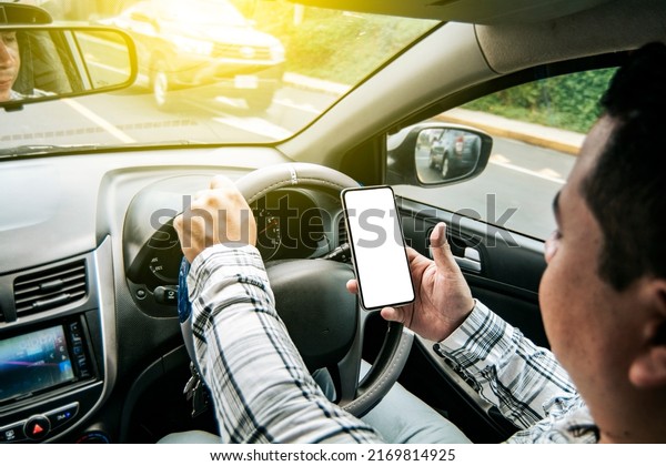 Distracted driver using the cell phone while\
driving, Man using his phone while driving, Person holding the cell\
phone and with the other hand the steering wheel, Concept of\
irresponsible\
driving