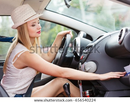 Distracted driver. Young attractive woman looking for something in vehicle interior while driving the car.