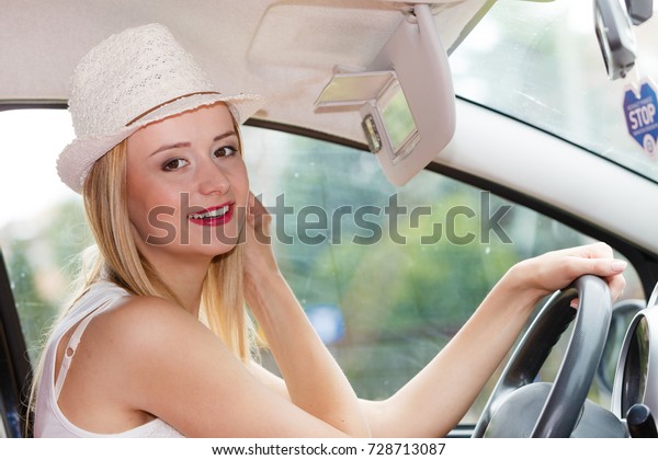 Distracted driver. Young attractive woman looking in\
mirror while driving the\
car.