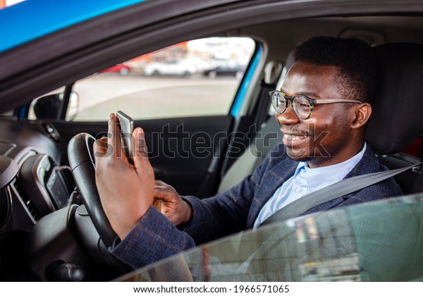 Distracted\
driving can increase the chance of a road accident. Portrait of a\
happy man texting and driving in his car on his cell phone.\
Businessman using mobile phone in the\
car
