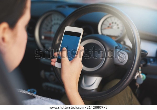 Distracted driving. Shot of a woman using a\
phone while driving.