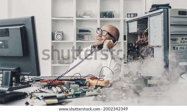 Distracted lazy technician talking on the phone\
while a broken computer is\
burning