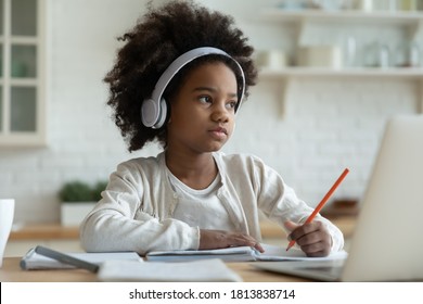 Distracted From Learning Little Mixed Race Kid Girl In Headphones Looking Away, Feeling Tired. Thoughtful Biracial Small Primary School Learner Stuck With Difficult Task Homework, E-learning Concept.