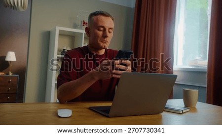 Distracted man worker remote work laptop home. Guy receive cool spicy sms mobile cell phone chatting. Male employee texting message. Ceo person take break rest. Online computer freelance distant job.