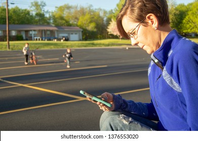 Distracted Parent Plays On Phone While Kids Play In The Background