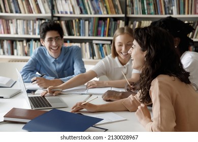 Distracted from preparing college project happy young laughing diverse classmates having fun, telling jokes, enjoying carefree pause time together, sitting at table in library, friendly communication. - Powered by Shutterstock