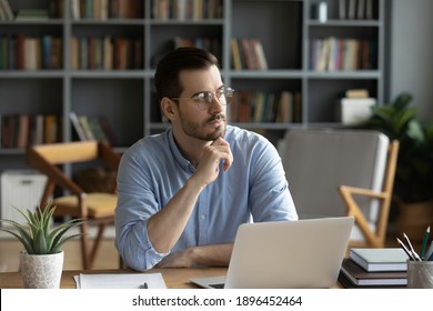 Distracted From Work Pensive Young Caucasian Man In Glasses Looking In Distance, Thinking Of Problem Solution Or Planning Workday Sitting Alone In Modern Home Office, Business Vision Concept.