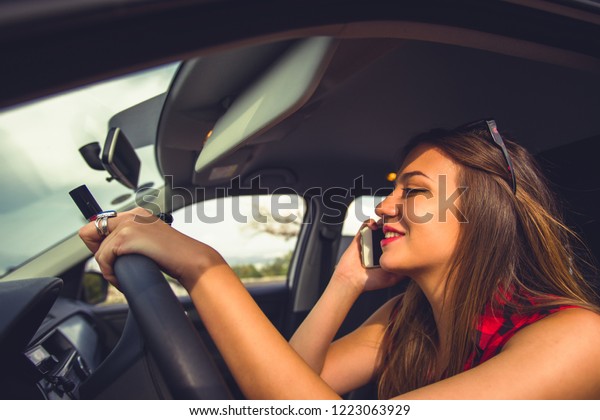 Distracted young business\
woman driver using a smartphone and texting while driving a car on\
a highway