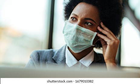 Distraught Black Businesswoman Wearing Face Mask While Being In The Office And Looking Away. 