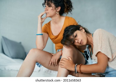 Distraught Gay Woman Leaning On Her Girlfriend's Leg After A Quarrel At Home.