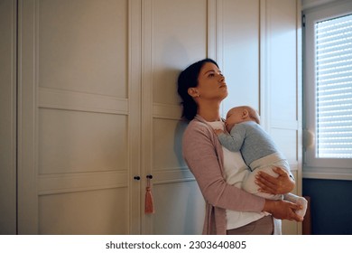 Distraught mother thinking of something while her baby is napping in her arms. Copy space.  - Powered by Shutterstock