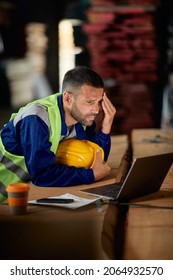 Distraught Worker Using Laptop While Working At Wood Warehouse. 