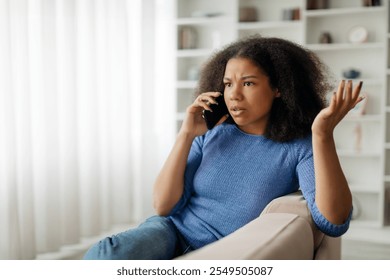 Distressed African American woman have phone conversation, sitting on the sofa at home - Powered by Shutterstock