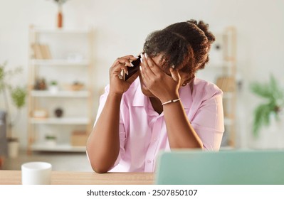 Distressed african american woman working in the office, feeling stressed and overwhelmed during a difficult phone call. Challenges of business, burnout, and financial problems, like a bankruptcy. - Powered by Shutterstock