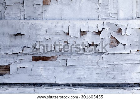 Distressed building wall with white aged paint chipping off