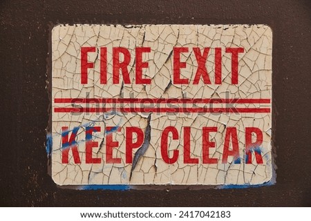Distressed Fire Exit Sign on Dark Wall - Vintage Safety Neglect