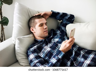 Distressed Man Laid On The Couch Using A Smarphone