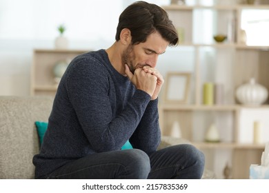 Distressed Man Sat Alone On The Sofa