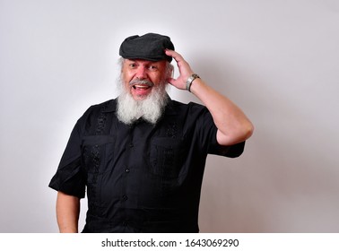 Distressed old man with a pained look. Mature gentleman with a newsboy cap and black guayabera shirt and long white beard.