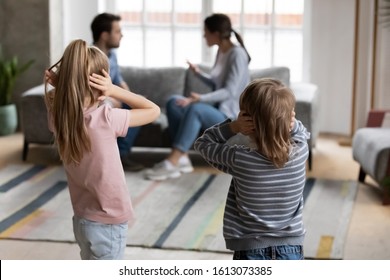 Distressed small kids brother and sister cover close ears avoid listening to parents quarrel fight at home, sad little siblings suffer from family adult conflicts or disputes affecting children health