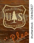 Distressed wooden sign with carved US Forest Service and Department of Agriculture logo at a camp site.