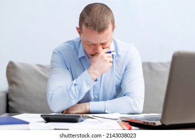 Distressed Young Man Sit At Desk Paying Bills Feel Stressed Having Financial Problems. Unhappy Upset Male Frustrated By Debt Or Bankruptcy Managing Household Budget Or Expenses.