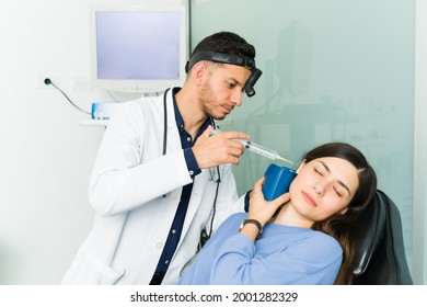 Distressed Young Woman Getting Her Ears Cleaned. Otolaryngologist Doctor Removing Earwax With Water And A Syringe